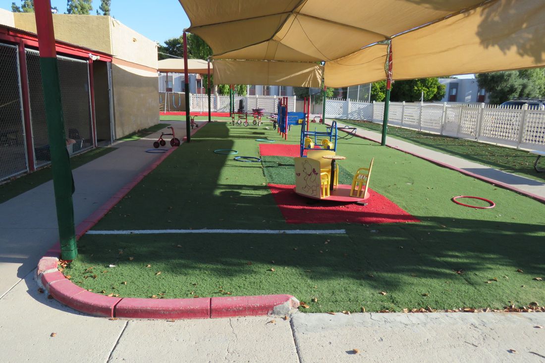 The shaded play yard at Nana&rsquo;s: green turf and shade sails overhead.