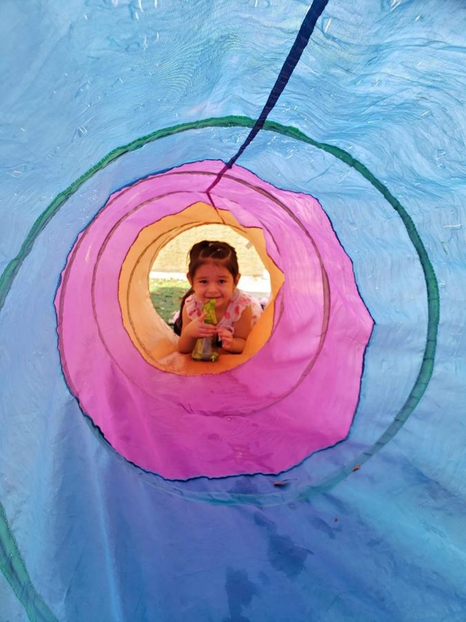 A child peeking out of a play tunnel at Nana&rsquo;s