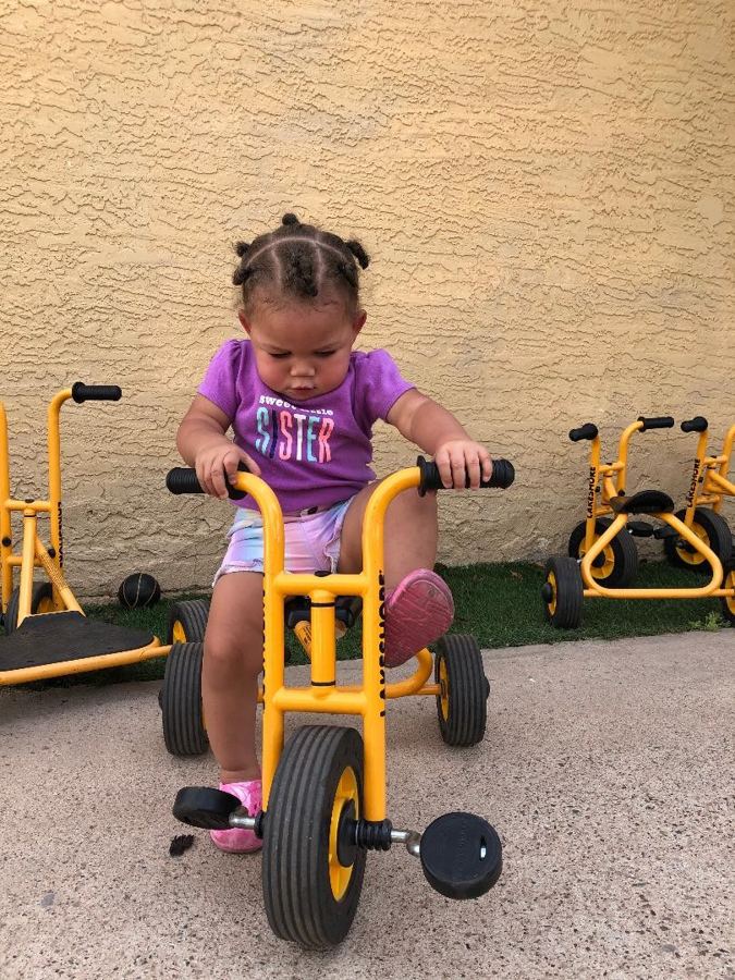 A toddler riding a tricycle at Nana&rsquo;s