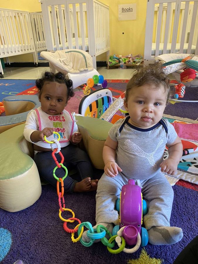 Two babies playing with a toy chain