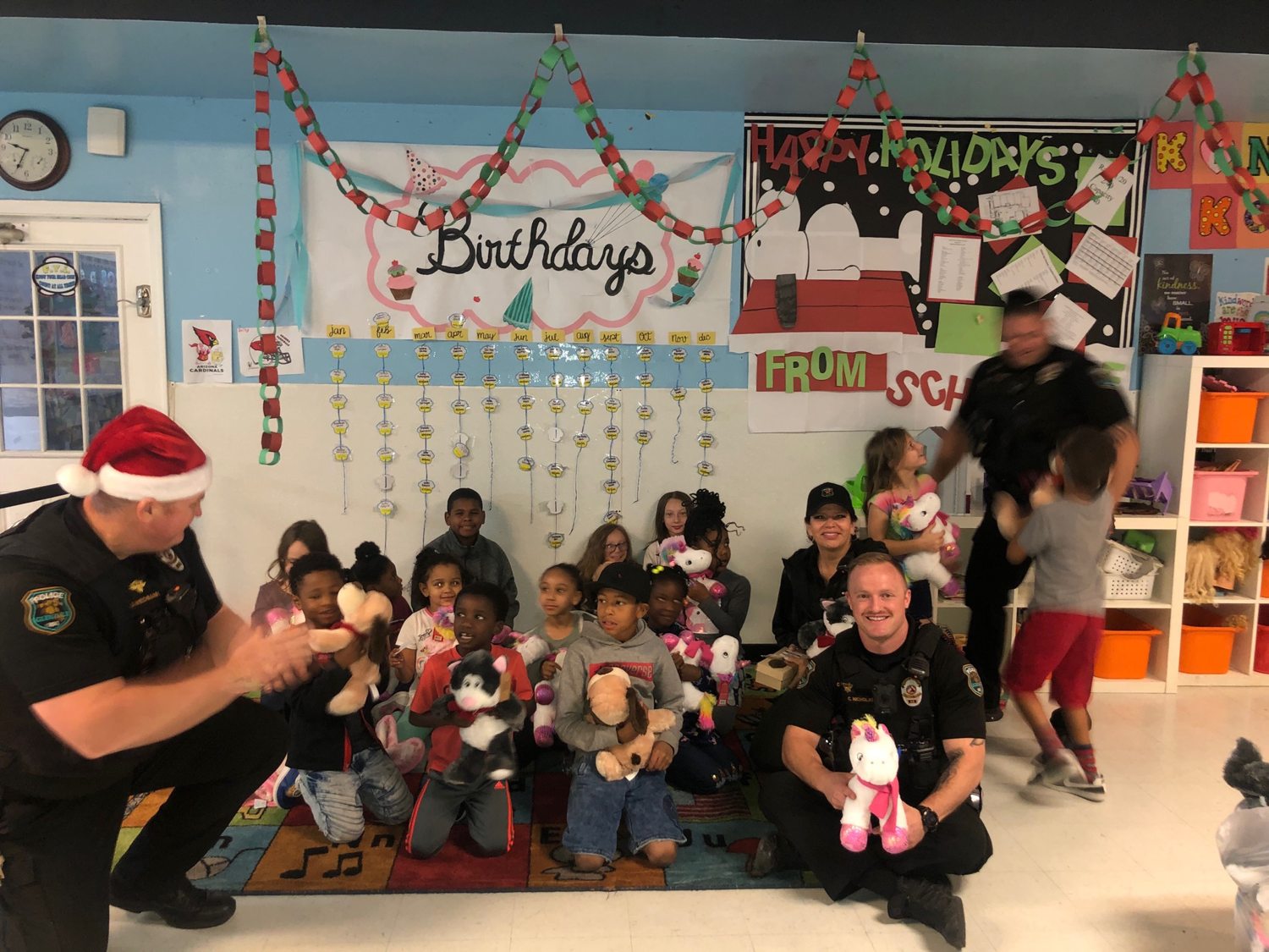 Glendale police officers handing out stuffed animals to the children at
               Nana&rsquo;s, holiday decorations on the walls.