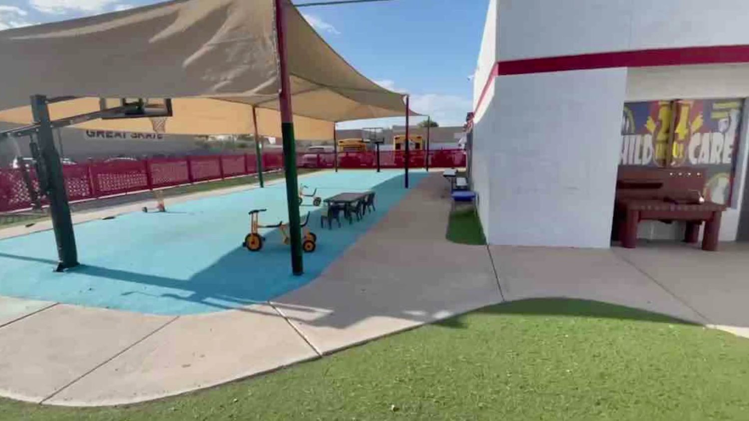The play yard alongside the building, trikes lined up on the turf